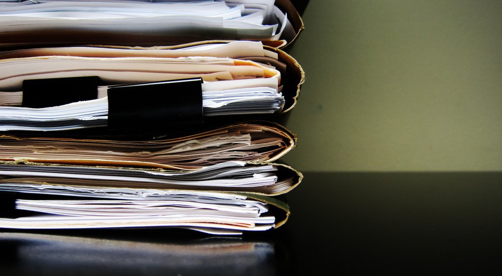 Stack of papers in folders on a table.