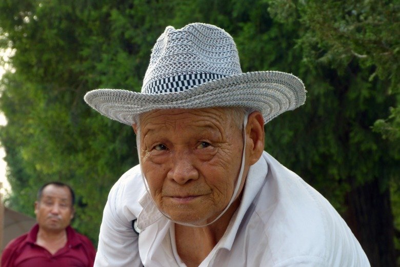 decorative, showing an older Chinese person in a hat with strap.