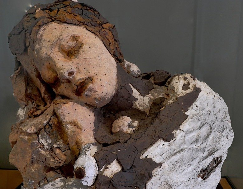 Photo of sculpture of sleeping human torso and head.
