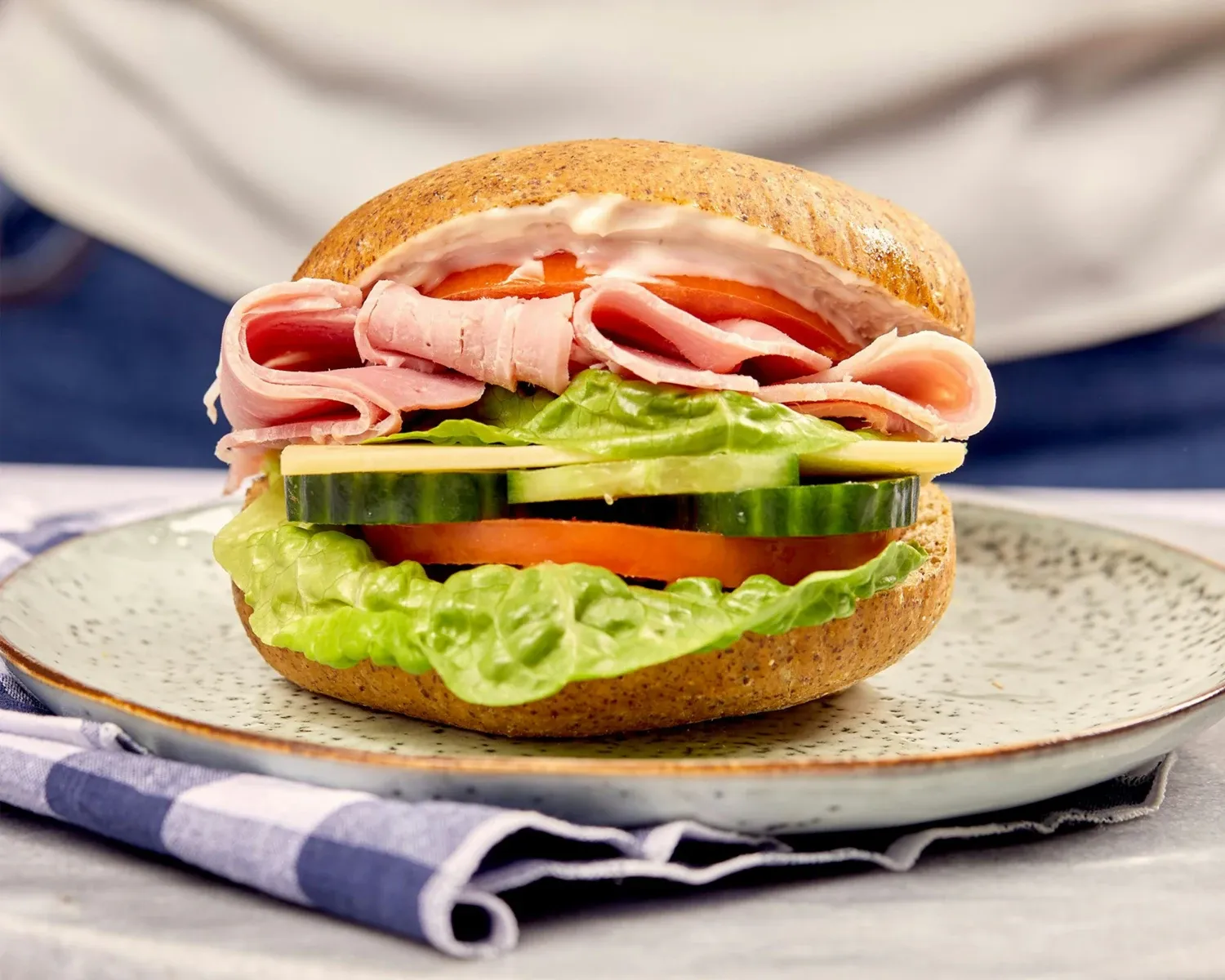 A bread roll with cheese, ham, tomato, cucumber and lettuce