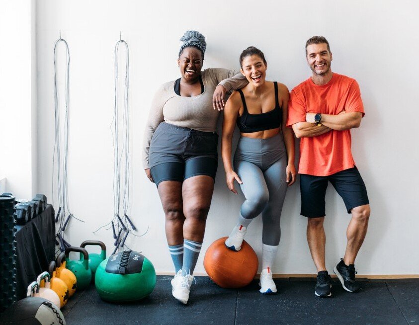 Three persons standing at the wall in a gym.