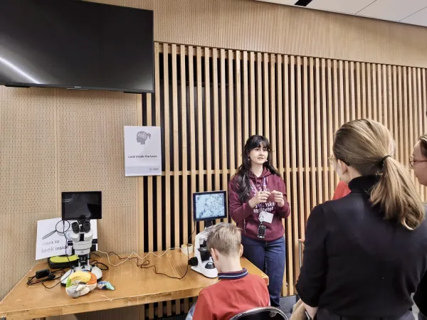 People stading around a microscope station, with a volunteer explaining what they are seeing