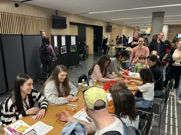People sitting at a table, taking part in a hands-on demonstration of brain signals.