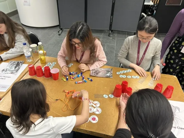 People sitting at a table, taking part in a hands-on demonstration with a mechanical claw.