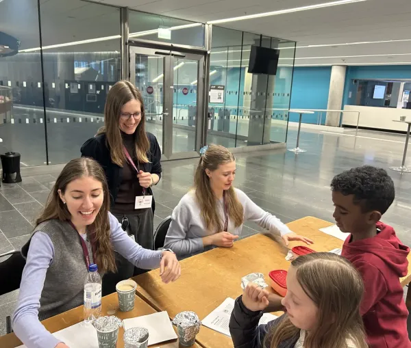 People standing next to a table with containers covered in aluminum foil for the smell workshop.
