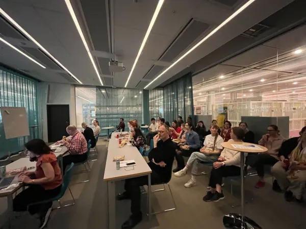 Group photo of people sitting in different rows in a large conference room with glass walls.