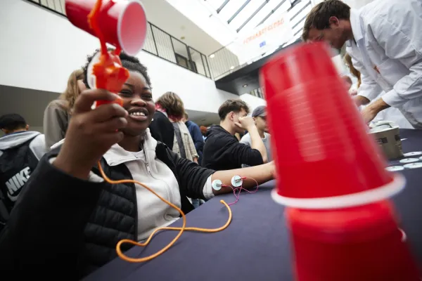 Girl holds a red plastic claw attached to a cord attached to her forearm at the other end (to measure hand movements)