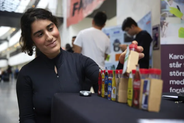 A girl looks at small bottles with the names of various famous drinks.