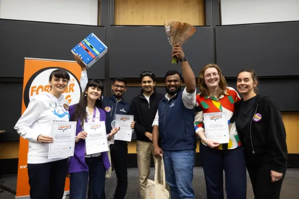 Seven researchers holding diplomas and flowers.