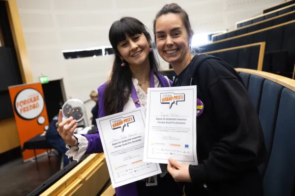 Two women holding diplomas.