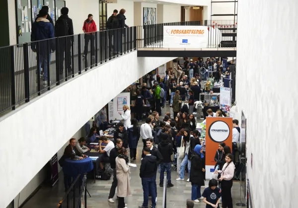 Many people around exhibition tables in a light and spacious room.