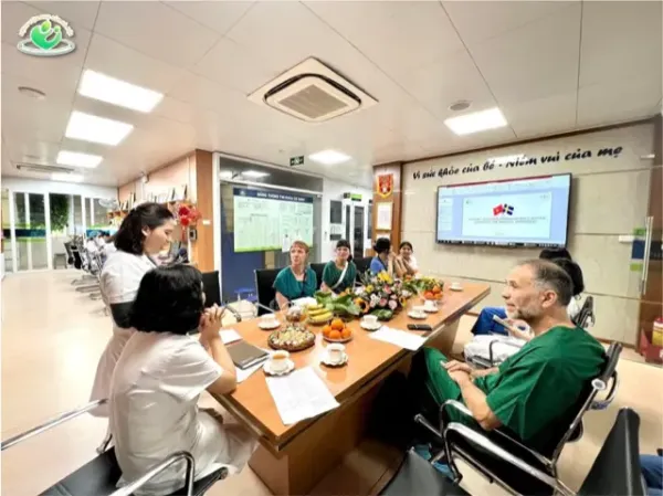 Nicolas together with the neonatal team around a table in hosital clothes to discuss clinical practice at the NICU, Phu San Hospital.