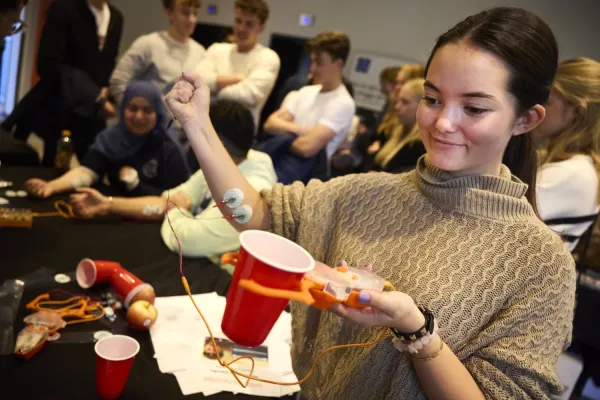 High school girl is holding a claw and has cords on one arm.
