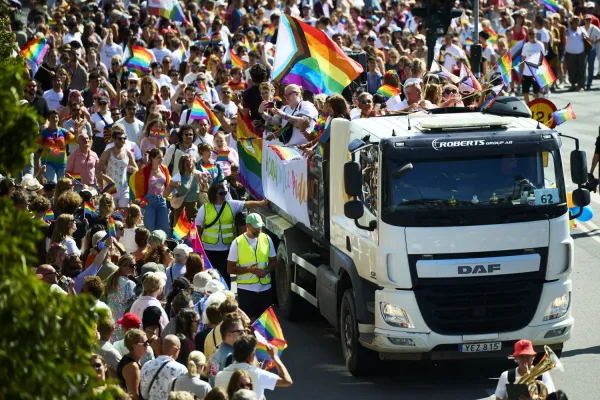Picture taken from futher away showing the truck with a big group of people behind it with rainbowflags.