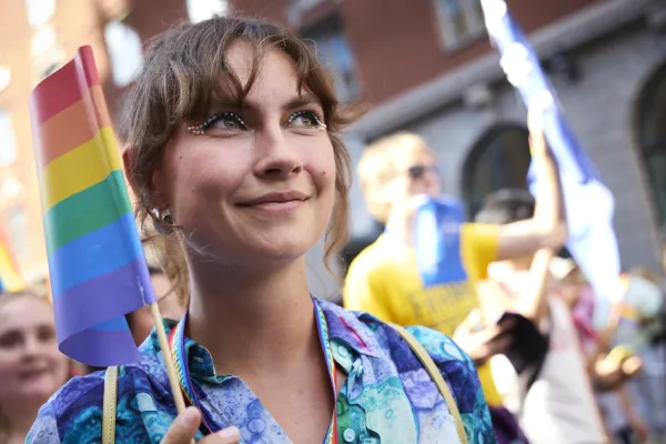 Elinor Lundevall holds a rainbow flag ans has small gemstones decorated around her eyes.