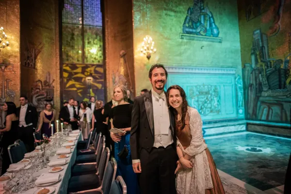 Two happy guests stand in the golden hall and look into the camera.