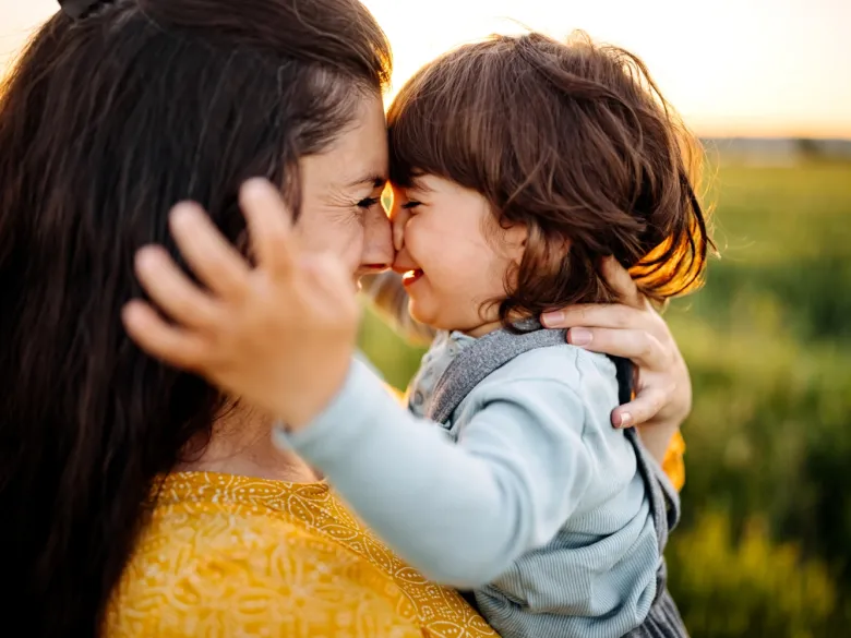 Mother and child cuddling outdoors.