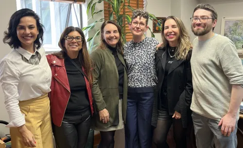 Six people standing together facing the camera in an office