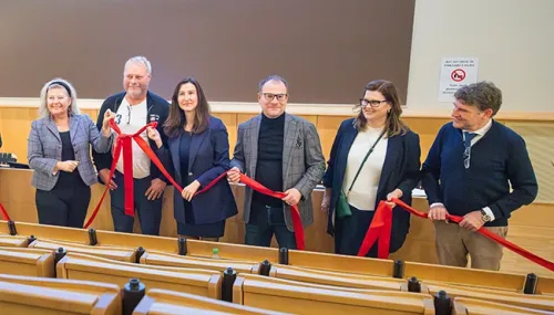 People on a stage tying together a red ribbon.
