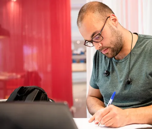 A person works at a desk with a pen and computer.