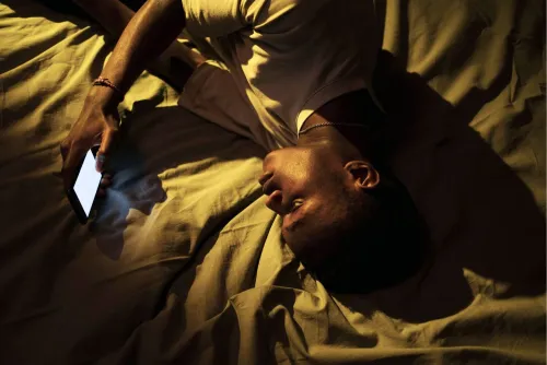 Man lying in bed scrolling his phone