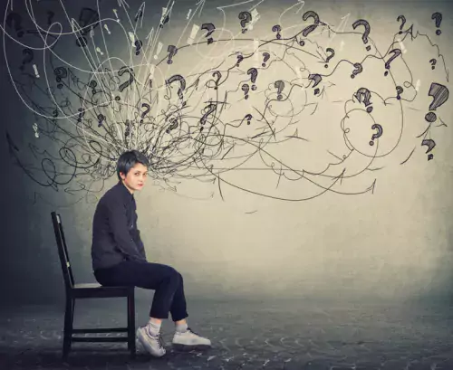 Woman sitting on a chair with animated ligns and question marks over her head.