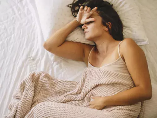 Young woman in bed with headache.