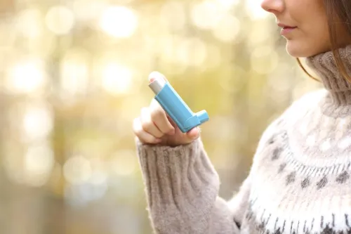 Women holding asthma inhaler ready to use