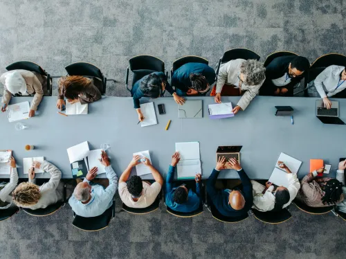 People working together on either side of a long, rectangular table, photographed from above.