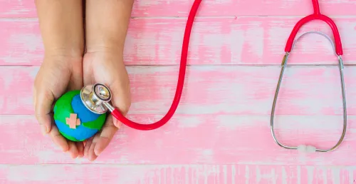 Symbolic illustration: hands holding a globe, which is being examined with a stethoscope.