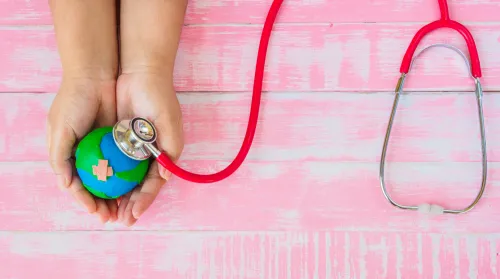 Symbolic illustration: hands holding a globe, which is being examined with a stethoscope.