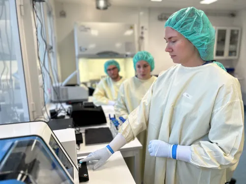 People wearing protective suits in a laboratory environment.