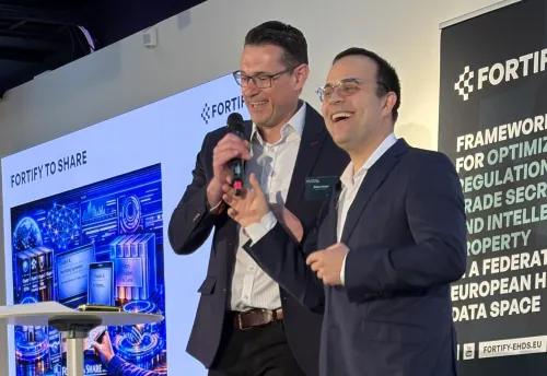 Two men standing on a podium during a conference. They are happy.