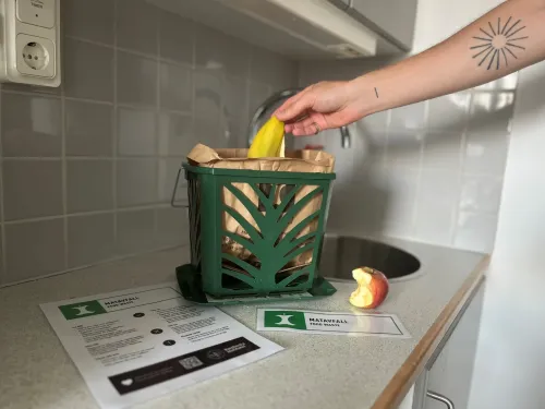 A green container with a brown paper bag in a kitchen setting.