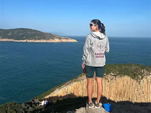Woman in a KI hoodie standing on a mountain looking at the water