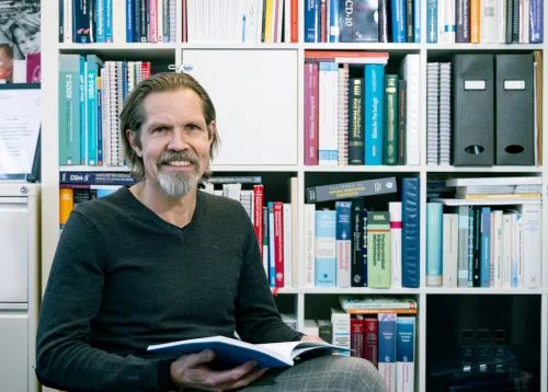 Smiling man infront of a book case.