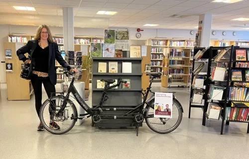 Pernilla Alencar Siljehag has finished the tandem tour and is now standing in the library leaning against the tandem bike.