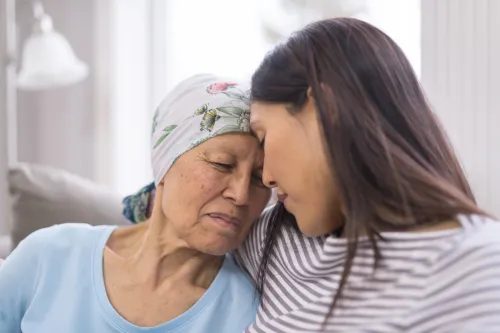Photo of elderly woman with cancer hugging her daughter.