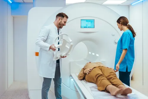 women undergoing MRI examination, man and women in hospital clothes standing beside her.