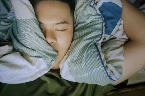 A young person&#039;s sleeping face sourrounded by duvet and pollow.