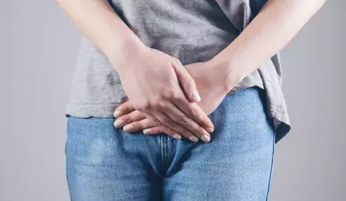Woman with jeans holding her hands ifront of tummy.