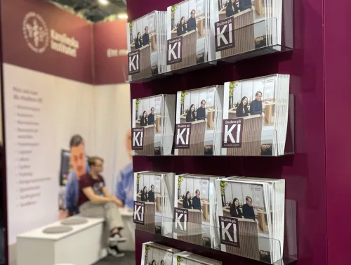 A shelf with KI&#039;s education catalogs in the foreground and a student sitting down in the background.