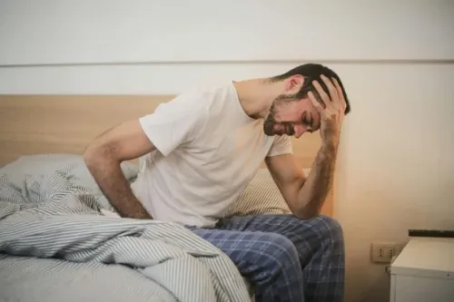 Man sitting on bedside wearing pyjamas