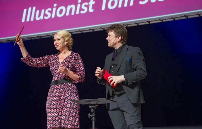 Karin Jensen holding a stick on stage with Tom Stone.