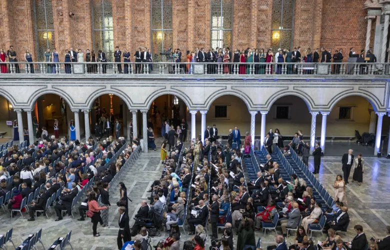 Overview of the Blue Hall, Stockholm City Hall. Some people have taken their seats while others are standing on the balustrade.