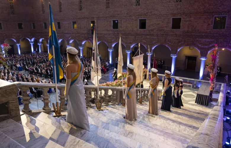 Student marshals stand along the marble stairs in the blue hall and have placed the flags.