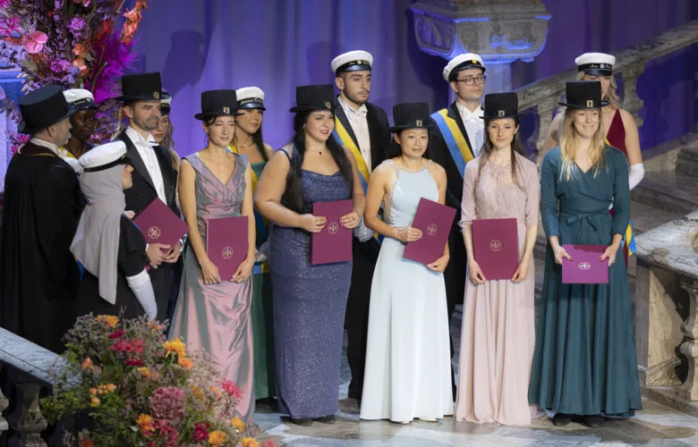 Students and PhD&#039;s with their doctoral hats and diploma stand in the stairs in the Blue Hall.