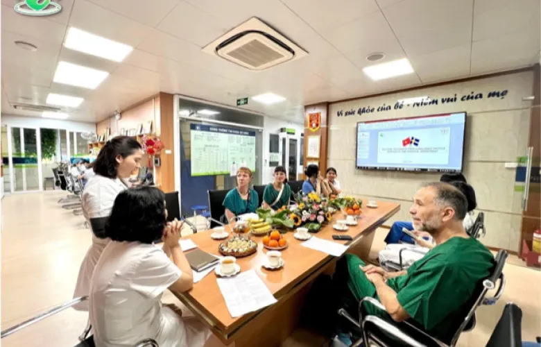 Nicolas together with the neonatal team around a table in hosital clothes to discuss clinical practice at the NICU, Phu San Hospital.